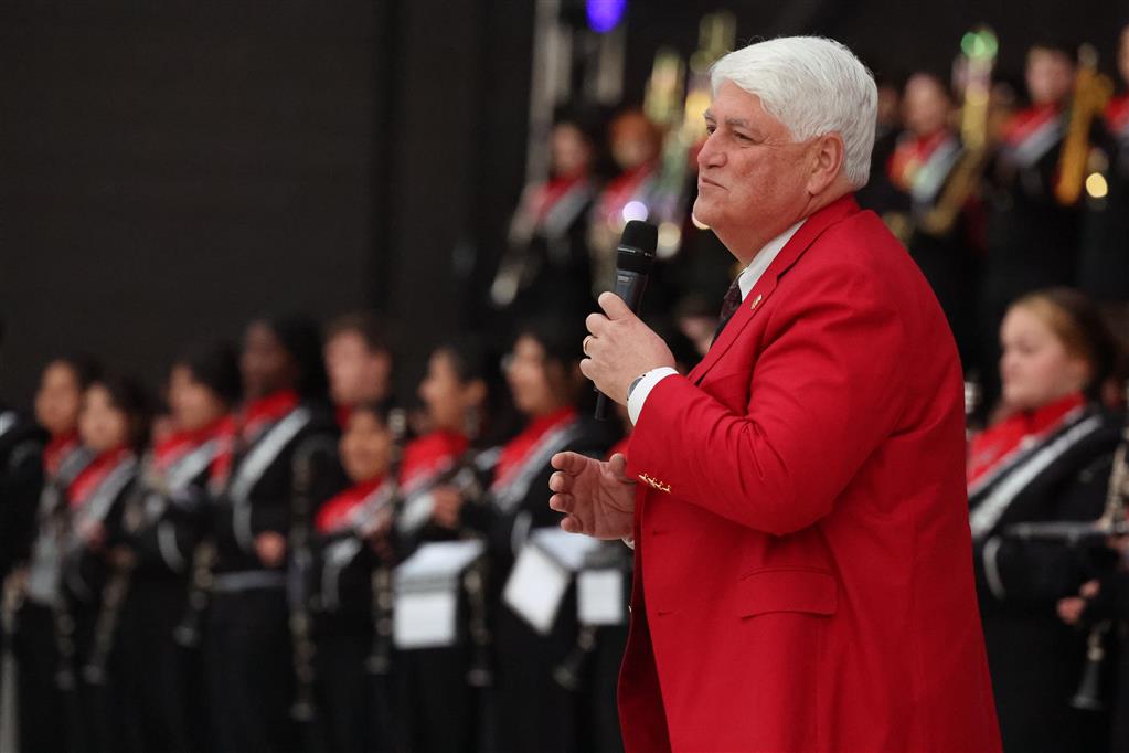 man standing in red jacket in front of band